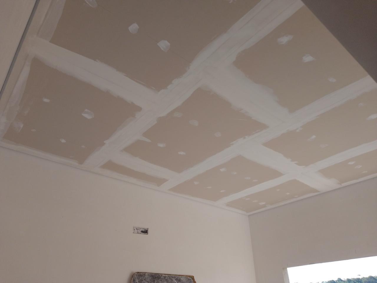 ceiling with drywall panels and joint compound, unfinished construction  — texto:  